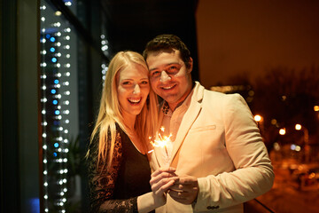 They met and sparks flew. Cropped portrait of a couple standing with sparklers on a balcony during a party.