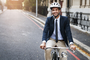 Safety first. Shot of a handsome young businessman riding his bicycle to work in the morning.