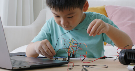 Asia people home school young small kid happy smile laugh self study online lesson excited make AI circuit toy. STEM STEAM digital class on laptop for active children play arduino enjoy fun hobby.