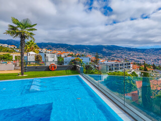 Fototapeta na wymiar Panoramic view pool with sunbeds in water, located on a mountain with a view to Funchal, capital of Madeira island