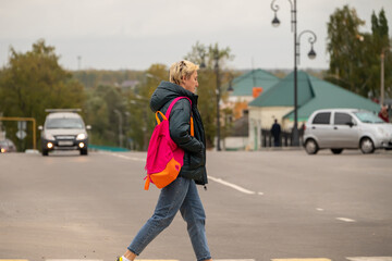 a girl in casual clothes crosses the road through a pedestrian crossing