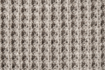 Texture of knitted woolen fabric of light brown color.