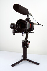 mirrorless camera and a connected microphone mounted on an electronic stabilizer on a white background
