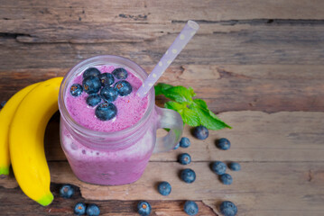 Blueberry mix banana smoothie purple colorful fruit juice milkshake blend beverage healthy high protein the taste yummy In glass,drink episode morning on a wooden background from top view.