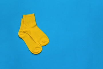 Neatly folded yellow socks on a blue background. Flat lay.
