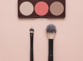 Large and small makeup brushes and a set of face shadows. Flat lay.
