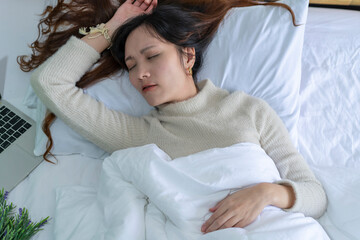 Asian woman grit her teeth on her mattress and snores loudly in her apartment bedroom. 