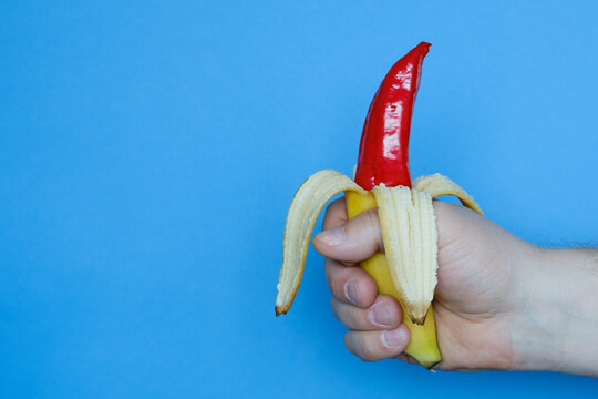 The hand is holding a banana with pepper sticking out of it.