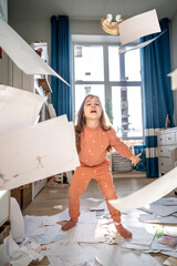 A girl among the mess and scattered sheets in the room.