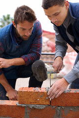 Showing the young one how its done. Shot of bricklayers at work. - obrazy, fototapety, plakaty