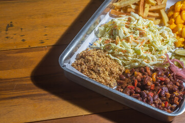 American barbecue tray with several garnishes, among them, coleslaw salad, Mac n cheese, barbecue beans, and french fries.