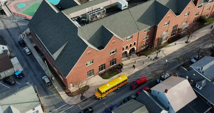 Modern American school building with school bus drop off. Playground painted for elementary recess. Aerial view.