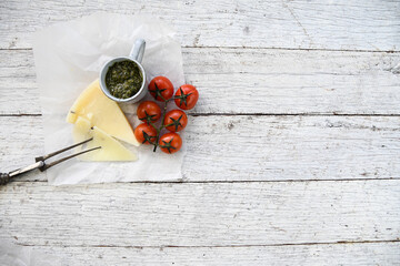 Cut cheese with pesto and mini tomatoes on the wine on a rustic white wooden table 