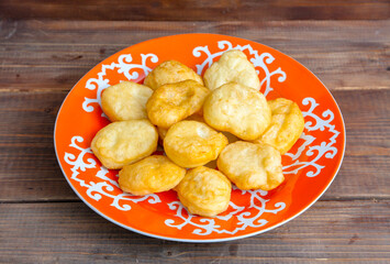 National Kazakh pastries baursaks in a plate on a wooden background