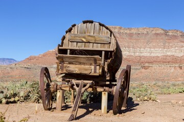 Replica of Old Vintage Wooden Wild West Stage Coach Wagon Wheel with Red Rock Canyon Cliffs Utah Landscape in the Background 