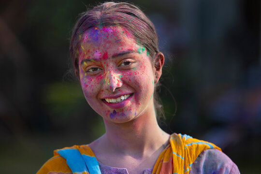 Close-up portrait of happy young woman with colourful face on Holi