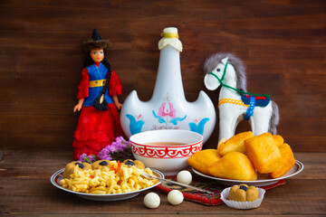 Kazakh still life on Nauryz, with national food: baursaks, zhent, kurt, chak chak and tea on a wooden background