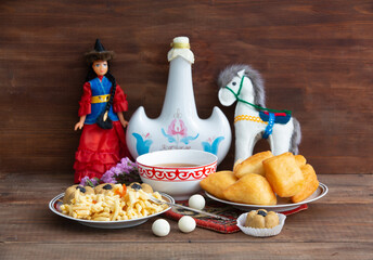 Kazakh still life on Nauryz, with national food: baursaks, zhent, kurt, chak chak and tea on a wooden background
