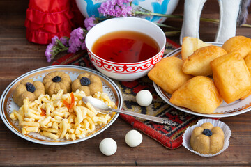 Kazakh still life on Nauryz, with national food: baursaks, zhent, kurt, chak chak and tea on a wooden background