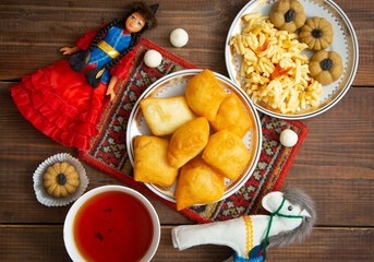 Kazakh still life on Nauryz, with national food: baursaks, zhent, kurt, chak chak and tea on a wooden background
