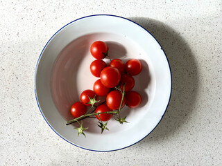 Old white tin bowl with tomatoes on the vine