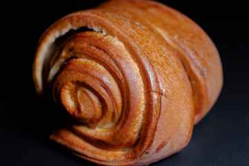 Fresh ruddy bun with jam on a black background. Close-up. Home bakery, food, cooking and pastry.