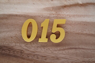 Golden Arabic numerals on a real brown and white wooden floor number 015