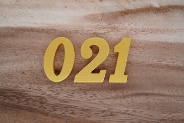 Golden Arabic numerals on a real brown and white wooden floor number 021