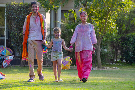 Young couple celebrating Holi with their daughter in the garden