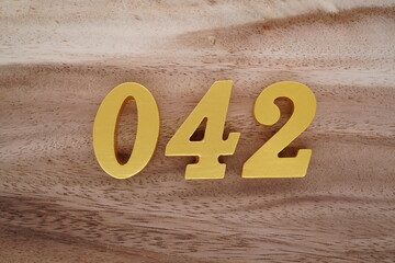 Golden Arabic numerals on a real brown and white wooden floor number 042