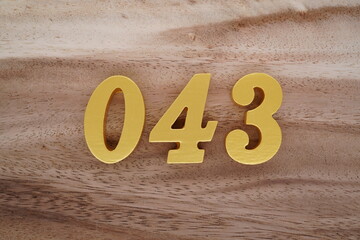 Golden Arabic numerals on a real brown and white wooden floor number 043