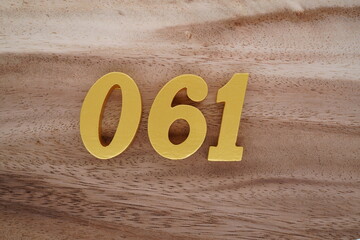 Golden Arabic numerals on a real brown and white wooden floor number 061