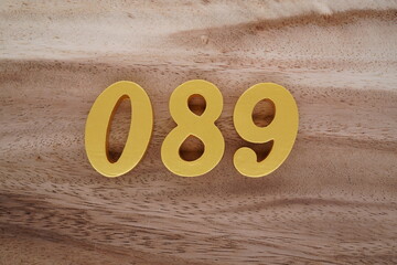 Golden Arabic numerals on a real brown and white wooden floor number 089