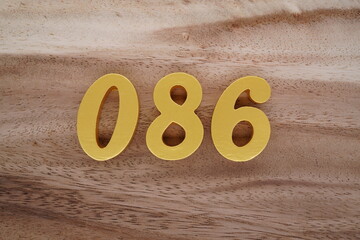 Golden Arabic numerals on a real brown and white wooden floor number 086