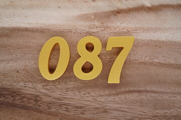Golden Arabic numerals on a real brown and white wooden floor number 087