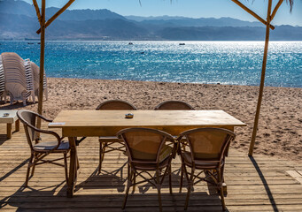Resting point with wooden floor, table and chairs on sandy beach of the Red Sea, Sinai peninsula, Middle East