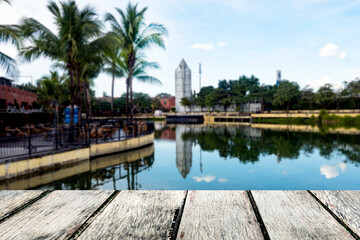 Fototapeta premium wooden bridge protruding in the middle of the river. For placing objects and background blur of water and tall buildings.