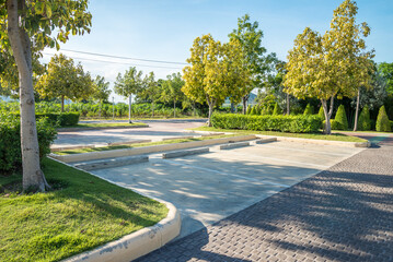 Empty space in city park outdoor concrete parking lot area with blue sky in summer season. Green nature gardening in car parking lot. Friendly environmental and transportation concept. - obrazy, fototapety, plakaty
