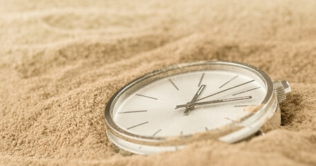 Pocket watch on a sand lost in time, closeup antique watch 