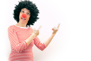 woman with a clown nose pointing with her hands. surprised face. white background. copy space
