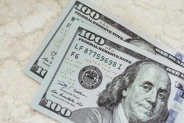 Two paper bills with a face value of one hundred dollars. Close-up