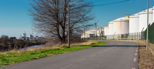 Fototapeta na wymiar Paysage industriel entre stockage d'hydrocarbure, arbre, canal, nature et usine métallurgique à Dunkerque
