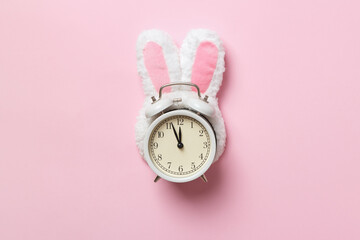 Easter time. Alarm clock in rabbit ears on a pink background.
