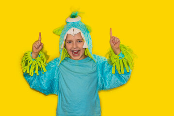 handsome schoolboy in monster costume. yellow background.Kid point finger up . Child cute face ....