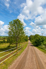 Fototapeta na wymiar Dirt road in the countryside with a power line and a fence