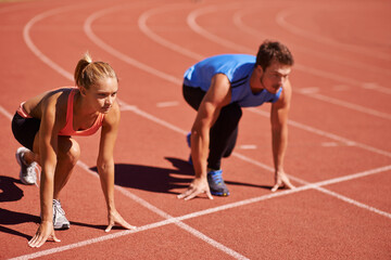 Ill take you on. Shot of two young people getting ready to race on an athletics track. - obrazy, fototapety, plakaty