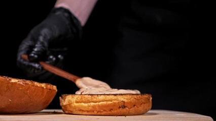 Craft burger is cooking on black background in black food gloves. Consist: sauce, lettuce, tomato,...