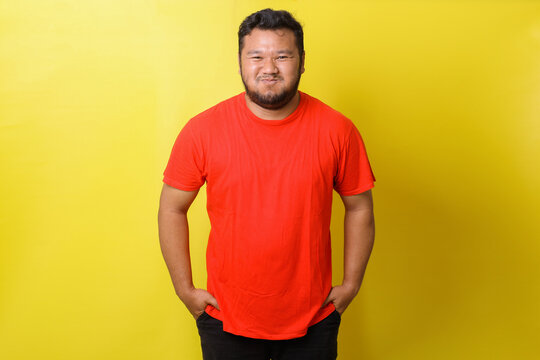 Asian Fat Man In Red Tshirt Is Simpering Smile  Isolated On Yellow Background 