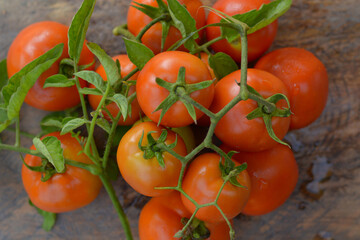 Tomatoes are attached to branches and leaves. placed on the wooden floor from the top corner