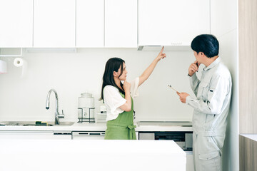 キッチンで話す作業着姿の男性と女性（換気扇・クレーム）

